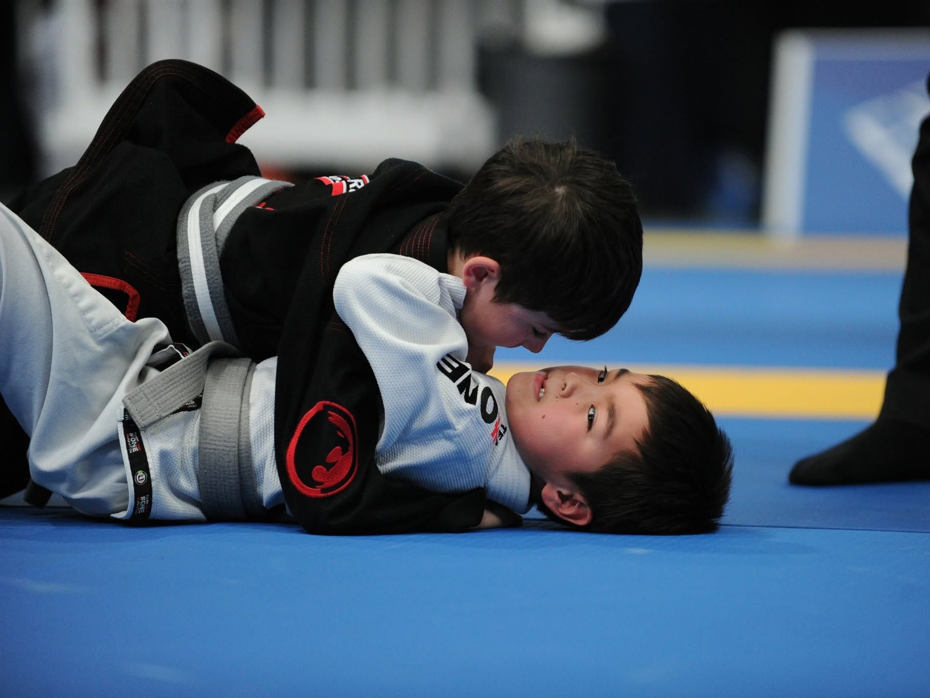 Dos niños de Renzo Gracie Laval en el suelo durante el IBJJF Montreal Open 2026, uno con kimono negro y otro con kimono blanco