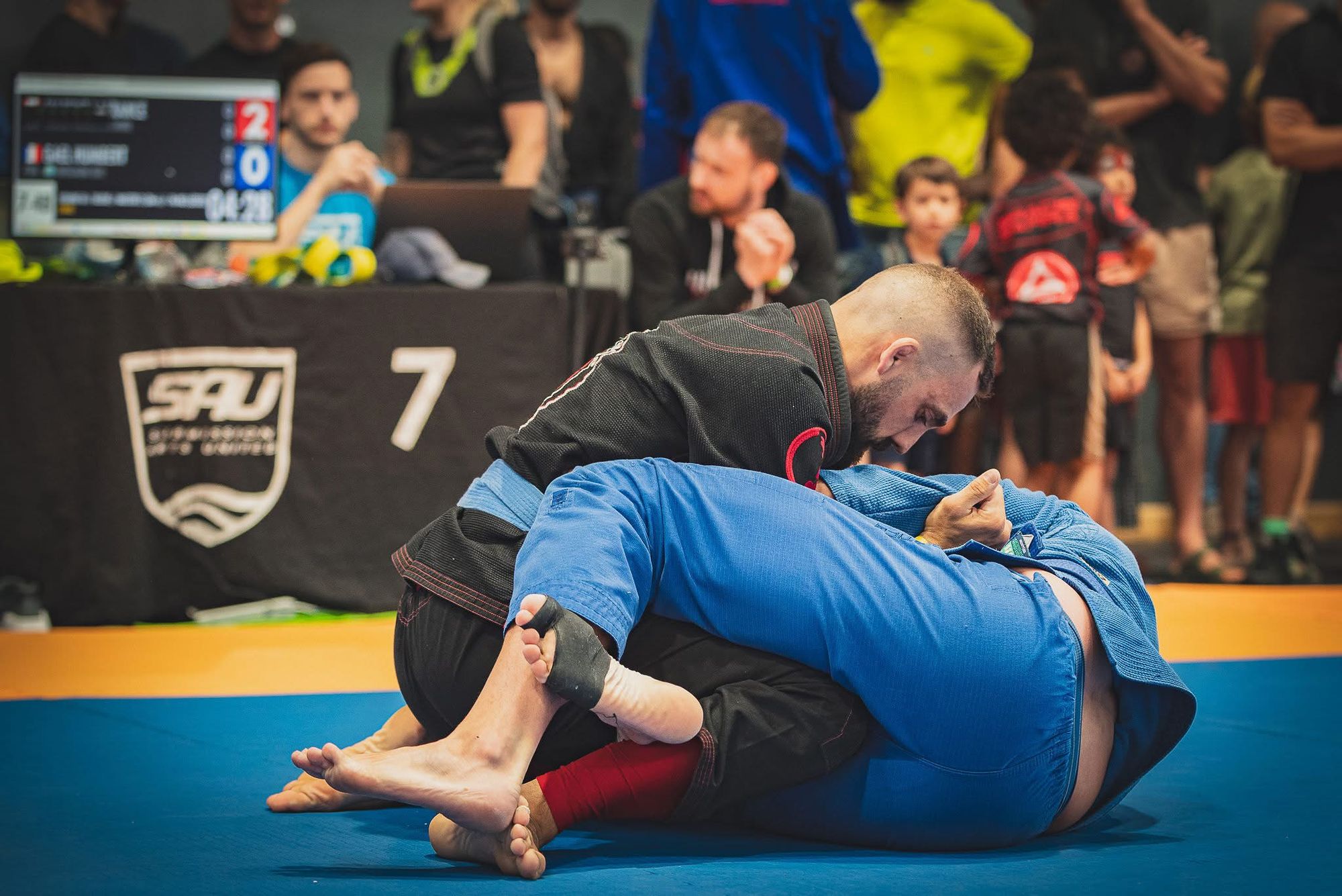 Two adults competing in a jiu-jitsu match at a tournament