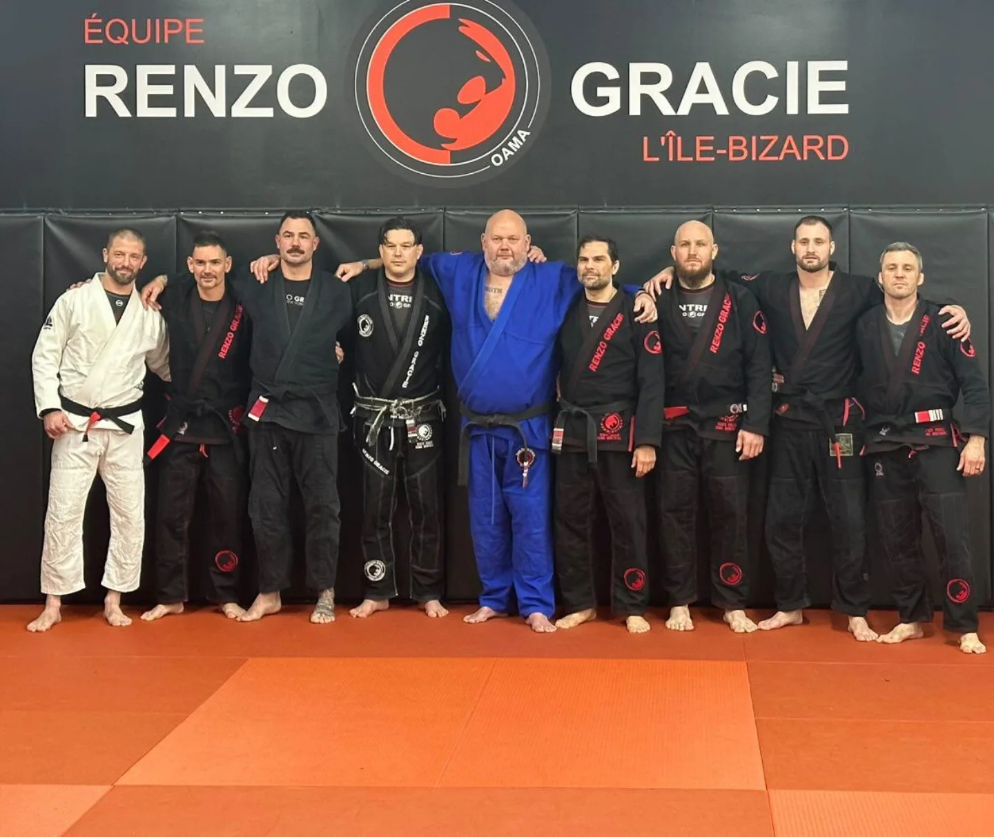 A row of practitioners in gis under a Renzo Gracie wall logo