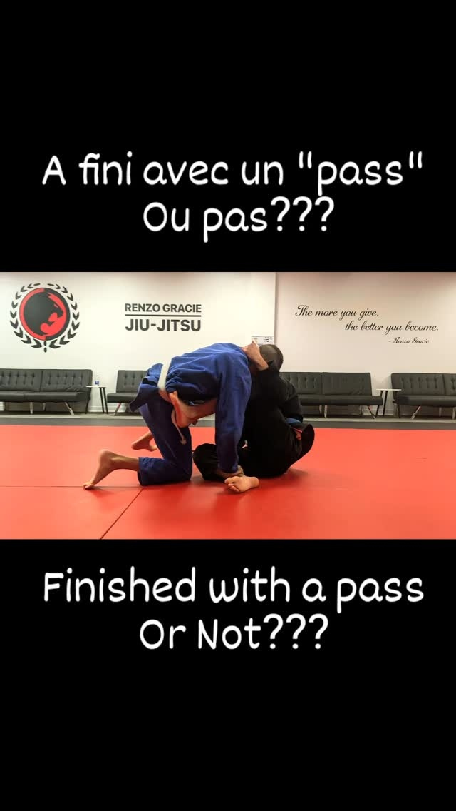 Two partners in blue and black gis battle in guard on red mats