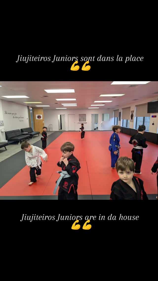 Young students in white, blue and black gis on the red mats