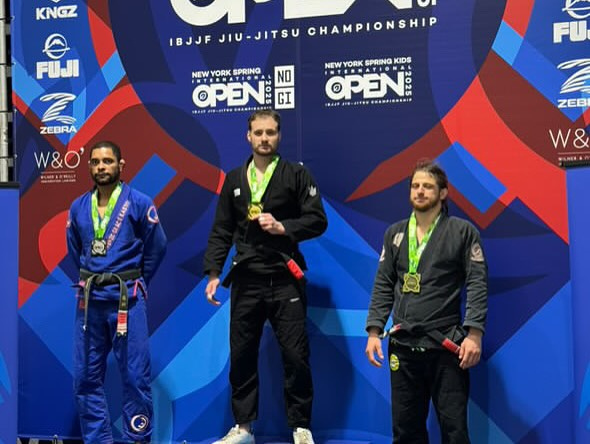 Trois compétiteurs ceinture noire sur un podium de tournoi