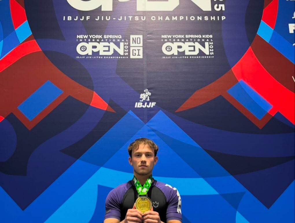 Un compétiteur en rashguard tient une médaille d’or