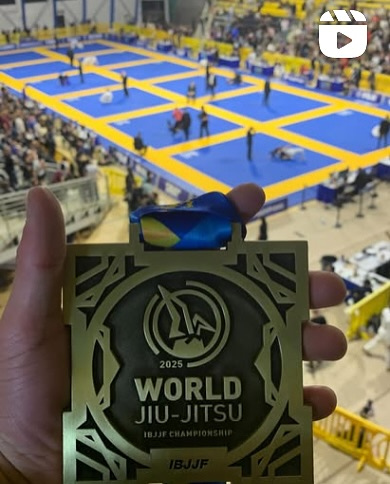 A 2025 World Jiu-Jitsu medal held up above the competition mats