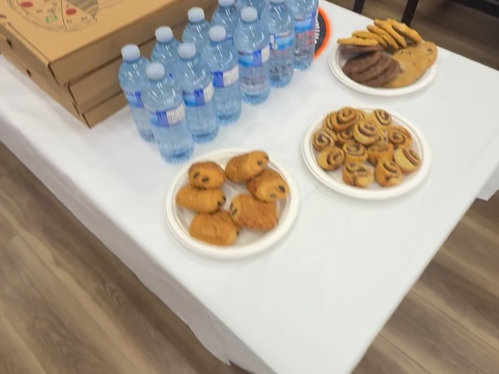 A party table with bottles of water, cookies and pastries