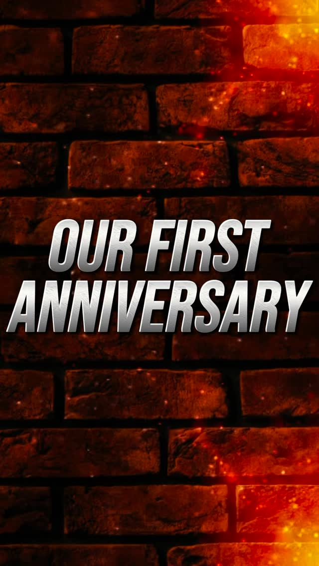 Our first anniversary em grandes letras prateadas sobre uma parede de tijolos vermelhos com chamas