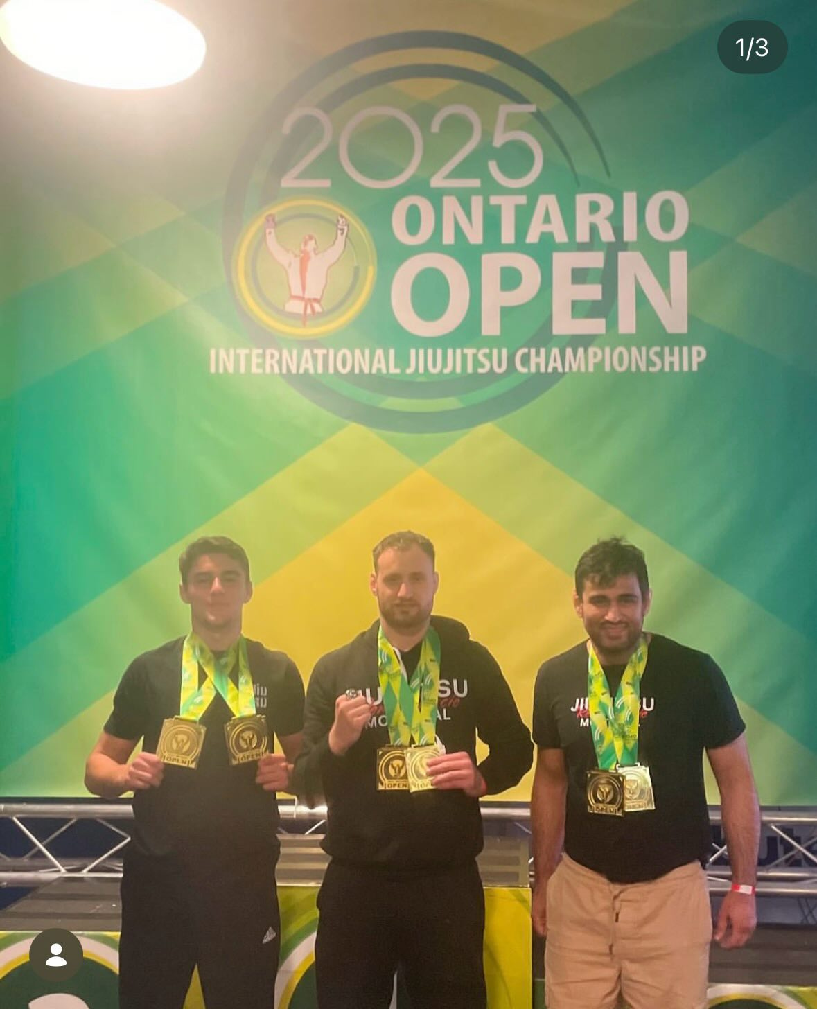 Three competitors in black team shirts wear gold medals in front of the Ontario Open banner