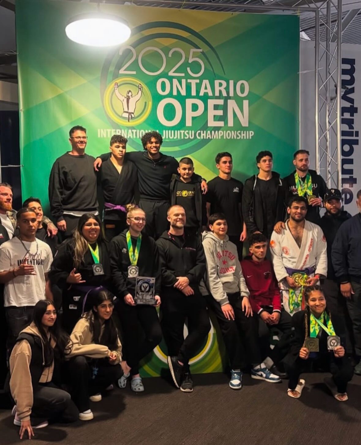 The team poses with medals in front of the 2025 Ontario Open banner
