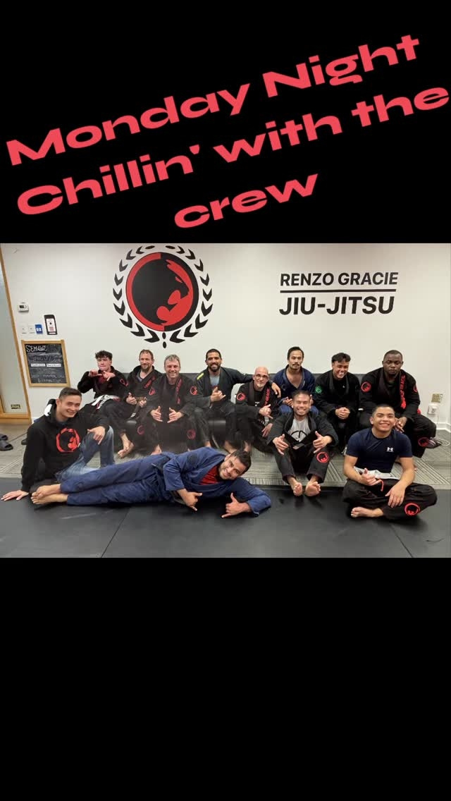 Adults in gis sit and lie on the mats under the Renzo Gracie Jiu-Jitsu sign