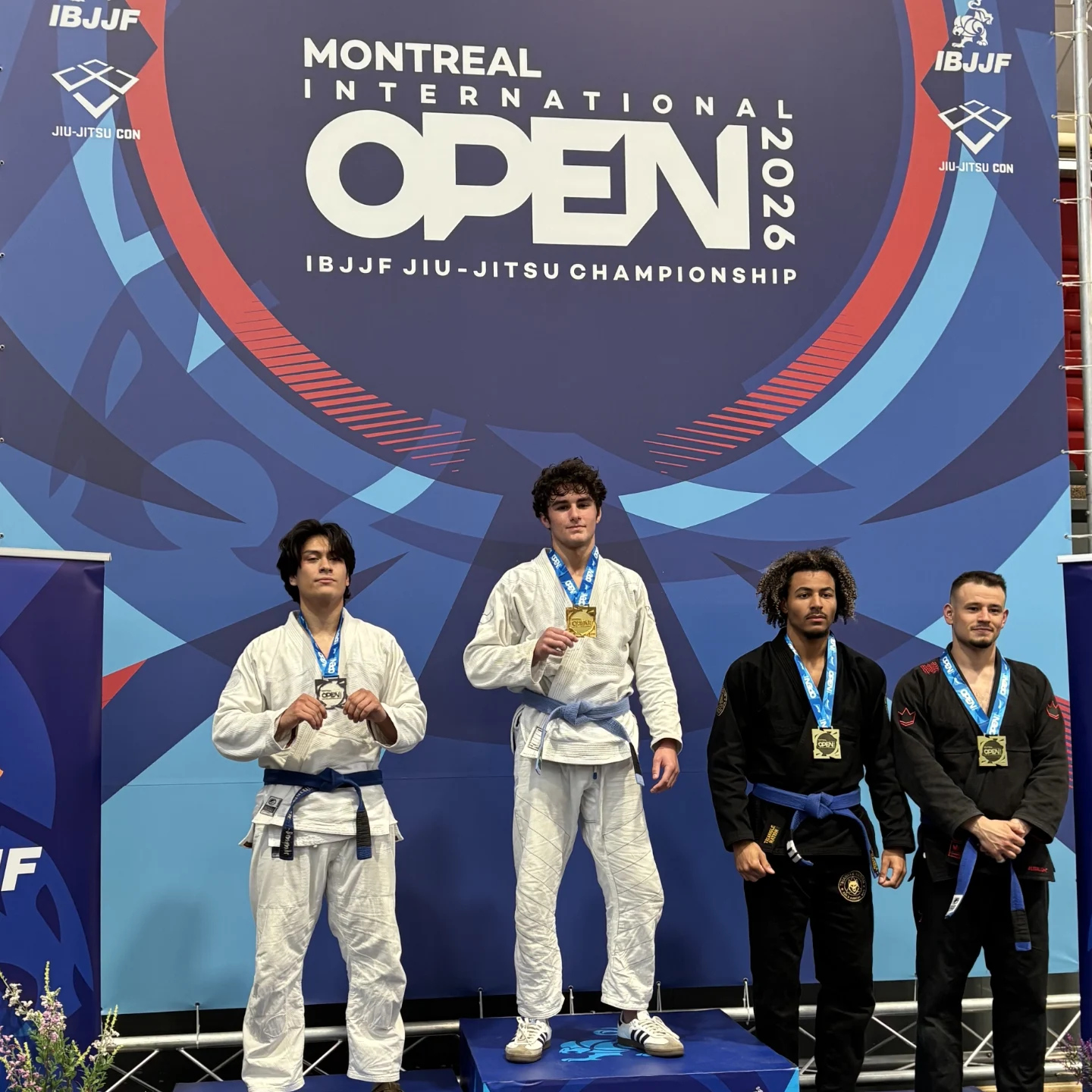 Quatre compétiteurs en kimono portent leur médaille devant la bannière Montreal International Open 2026