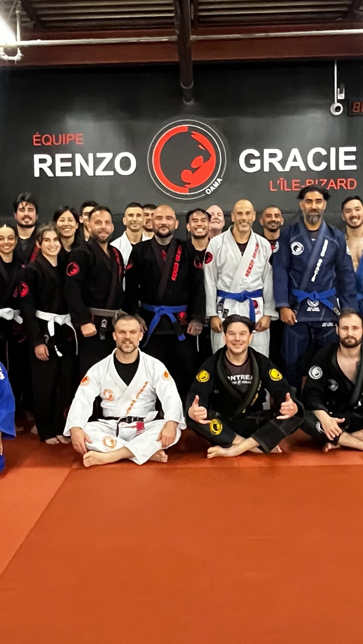 مجموعة كبيرة بزي الجوجيتسو على البساط أمام جدار Équipe Renzo Gracie L'Île-Bizard