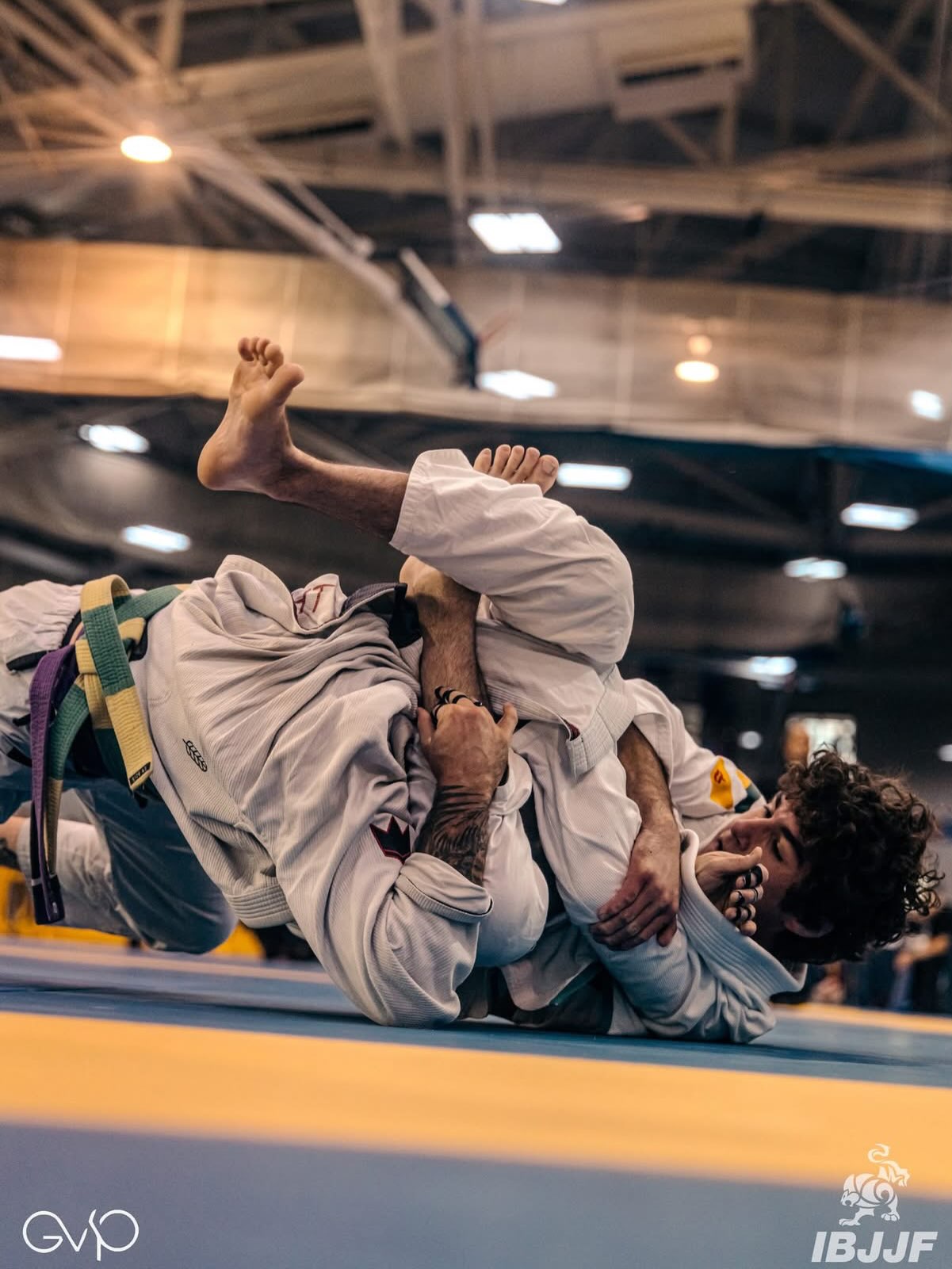 Dos competidores luchan en el suelo en un torneo IBJJF