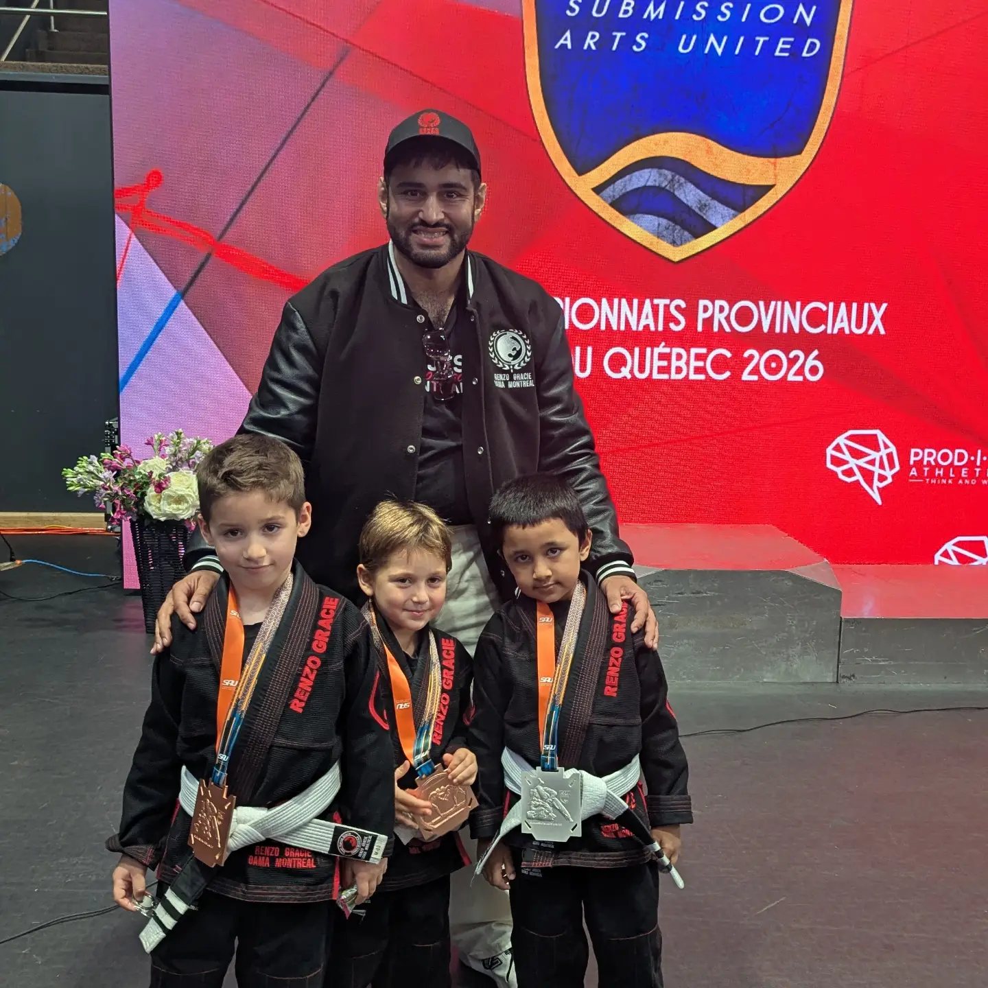 Three young competitors in black gis wearing their medals
